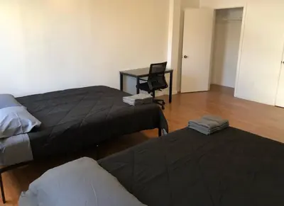 a room with two beds and a desk and a chair at Large apartment, sleeps up to 10 people comfortably, direct NYC Manhattan train only 5 minute walk away, MetLife Stadium FIFA World Cup 25 minutes away in Elizabeth