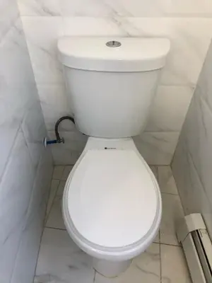 a white toilet in a white tiled bathroom at Large apartment, sleeps up to 10 people comfortably, direct NYC Manhattan train only 5 minute walk away, MetLife Stadium FIFA World Cup 25 minutes away in Elizabeth