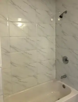 a white bathroom with a shower with a tub at Large apartment, sleeps up to 10 people comfortably, direct NYC Manhattan train only 5 minute walk away, MetLife Stadium FIFA World Cup 25 minutes away in Elizabeth
