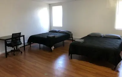 a room with two beds and a table and a desk at Large apartment, sleeps up to 10 people comfortably, direct NYC Manhattan train only 5 minute walk away, MetLife Stadium FIFA World Cup 25 minutes away in Elizabeth
