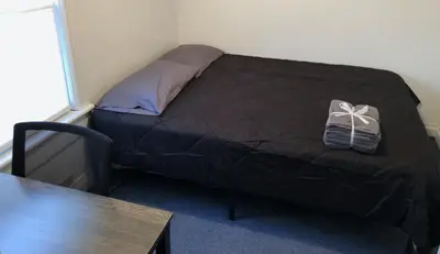 a bedroom with a bed with a black comforter at Private and cozy house with one bedroom and one bathroom, MetLife Stadium FIFA World Cup 35 minutes away in Perth Amboy