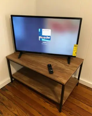 a television on a wooden table with a remote control at Private and cozy house with one bedroom and one bathroom, MetLife Stadium FIFA World Cup 35 minutes away in Perth Amboy