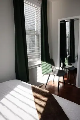 a bedroom with a bed and a chair in front of a window at Modern 2BR, Easy access to NYC in Jersey City