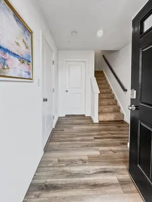 a hallway with white walls and a staircase with wooden floors at Luxurorious Townhome In Reading in Mount Penn