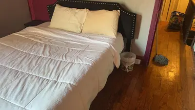 a bedroom with a bed with white sheets and a trash can at 2218 N Colorado Master Queen Room in Dogwood Acres