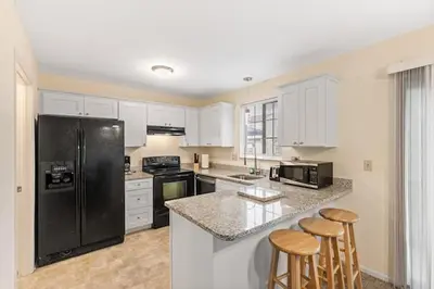 a kitchen with white cabinets and a black refrigerator at Comfy Stay Modern in Highspire