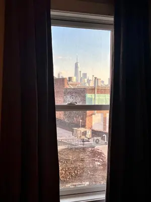 a window with a view of a city skyline at Charles Peak Condo - JC Heights in Jersey City