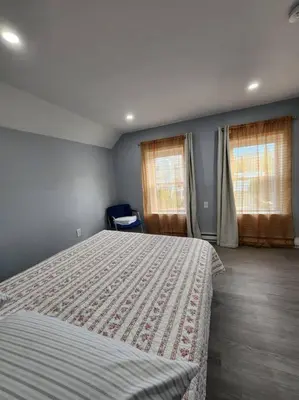 a bedroom with a large bed and two windows at Two-Bedroom Home 25 min to NYC free parking-UNIT-2 in Teaneck