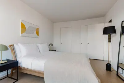 a white bedroom with a large bed and a table at Blueground Upper West Side nr parks wd NYC-1678 in New York