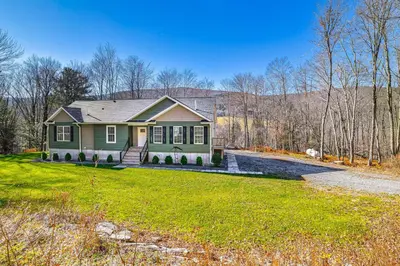 a green house on a field with a yard at Mountain Views and Brook Access Home in Arkville! in Arkville