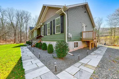 a green house with a porch and a yard at Mountain Views and Brook Access Home in Arkville! in Arkville