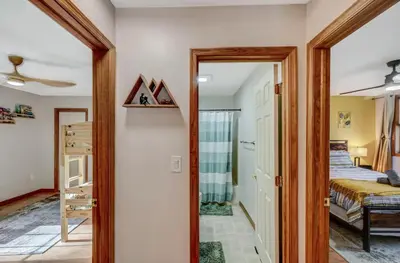 a hallway leading to a bedroom with a bed and a mirror at Locust Lake Livin Hot Tubfire Pitskiingpets in Pocono Lake