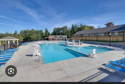 a large swimming pool with blue lounge chairs at POCONOS everything close to Luxury vacational home in the heart of poconos with 3 outdoor pools for the public of the Tobyhanna community in Tobyhanna