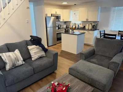a living room with a couch and a kitchen at POCONOS everything close to Luxury vacational home in the heart of poconos with 3 outdoor pools for the public of the Tobyhanna community in Tobyhanna