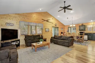 a living room with couches and a television and a table at Woodland Cabin Getaway in Greentown