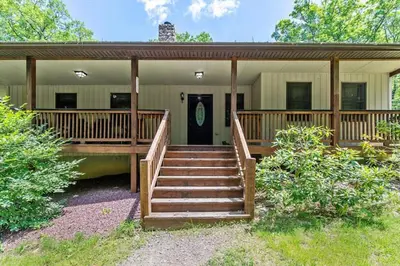 a home with a porch with stairs leading to the front door at Woodland Cabin Getaway in Greentown