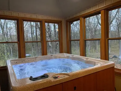 a large bath tub in a room with windows at Woodland Cabin Getaway in Greentown