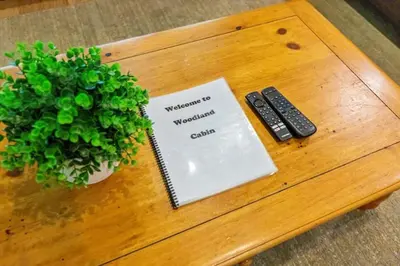 a table with a book and remote controls on it at Woodland Cabin Getaway in Greentown