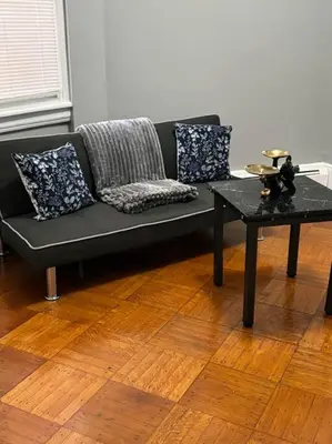 a black couch in a living room with a table at Spacious 3-bedroom Apartment Stunning Views NYC in Union City
