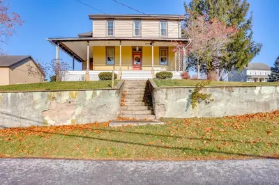 a yellow house with stairs in front of it at 3 Mi to Dtwn Charming Farmhouse in Mount Joy! in Mount Joy