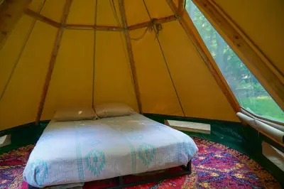 a bed in a tent with a large window at Lenape at Moon Valley Campground in Vernon Township