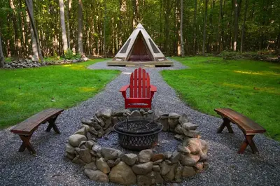 a fire pit with two benches and a tent at Lenape at Moon Valley Campground in Vernon Township