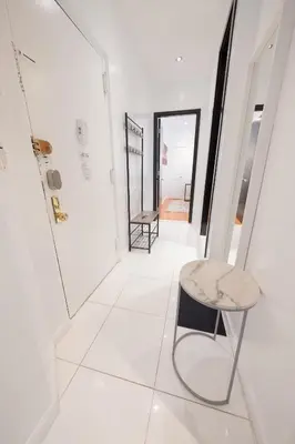 a white hallway with a chair and a mirror at 3 BD next to Central Park in New York