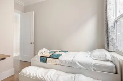 a bedroom with a bed with white sheets and a window at NYC Gateway, 30minutes from Manhattan in Jersey City