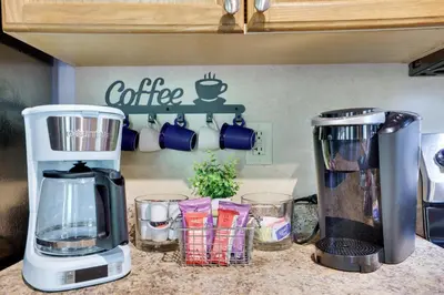 a kitchen counter with a coffee maker and cups at COZY COTTAGE Spacious 4Bdrm 2Bth, Hot Tub, Game Movie Room, Close to camelback skiing, Sauna Firepit, Arcades, Backyard Playground, 2 Min Walk To Pool, Lake, Beach, Basketball in Tobyhanna