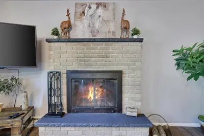 a living room with a brick fireplace at COZY COTTAGE Spacious 4Bdrm 2Bth, Hot Tub, Game Movie Room, Close to camelback skiing, Sauna Firepit, Arcades, Backyard Playground, 2 Min Walk To Pool, Lake, Beach, Basketball in Tobyhanna