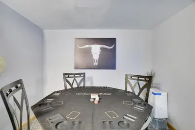 a table with two chairs and a bull painting on the wall at COZY COTTAGE Spacious 4Bdrm 2Bth, Hot Tub, Game Movie Room, Close to camelback skiing, Sauna Firepit, Arcades, Backyard Playground, 2 Min Walk To Pool, Lake, Beach, Basketball in Tobyhanna