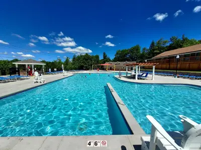 a large swimming pool with blue water at COZY COTTAGE Spacious 4Bdrm 2Bth, Hot Tub, Game Movie Room, Close to camelback skiing, Sauna Firepit, Arcades, Backyard Playground, 2 Min Walk To Pool, Lake, Beach, Basketball in Tobyhanna