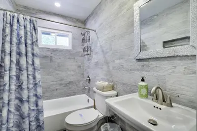 a bathroom with a sink and a toilet and a mirror at COZY COTTAGE Spacious 4Bdrm 2Bth, Hot Tub, Game Movie Room, Close to camelback skiing, Sauna Firepit, Arcades, Backyard Playground, 2 Min Walk To Pool, Lake, Beach, Basketball in Tobyhanna