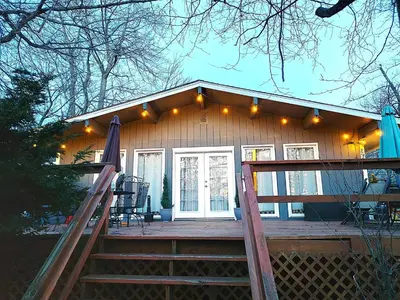 a small house with a porch with a patio at COZY COTTAGE Spacious 4Bdrm 2Bth, Hot Tub, Game Movie Room, Close to camelback skiing, Sauna Firepit, Arcades, Backyard Playground, 2 Min Walk To Pool, Lake, Beach, Basketball in Tobyhanna