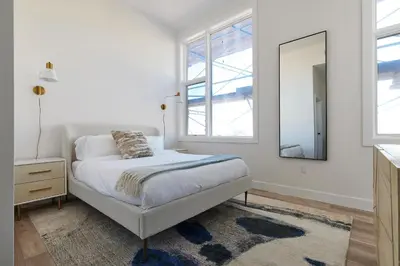 a white bedroom with a bed and a mirror at Prime Hoboken Lofts in Hoboken