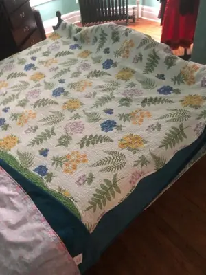 a bed with a blanket with flowers on it at Scenic easy go to TIMES SQUARE in North Bergen