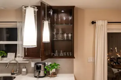 a kitchen with wooden cabinets with glasses on shelves at Enchanted Villa in Pocono Summit