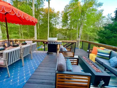 a deck with couches and a table and a grill at Enchanted Villa in Pocono Summit