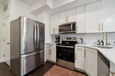a kitchen with white cabinets and a stainless steel refrigerator at Roof deck w city views - brand new 3bd 3ba in Philadelphia