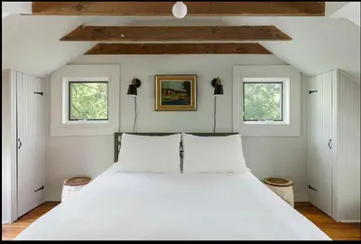 a bedroom with a large white bed with two windows at Private Creek and Large Yard at the Coziest Cabin in the Catskills in Margaretville