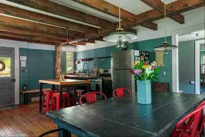 a kitchen with a table with a vase of flowers on it at Private Creek and Large Yard at the Coziest Cabin in the Catskills in Margaretville