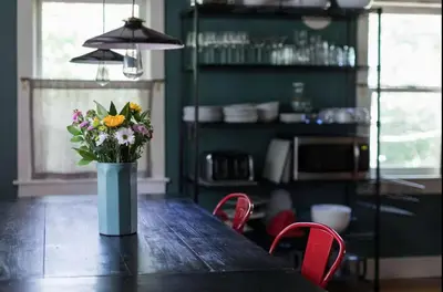 a vase of flowers sitting on a table in a kitchen at Private Creek and Large Yard at the Coziest Cabin in the Catskills in Margaretville