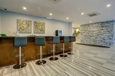 a lobby with a bar with blue chairs and a stone wall at Upscale NoLibs XL Studio - Pool & Gym in Philadelphia
