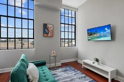 a living room with a green couch and windows at Modern NoLibs Studio - Pool & Gym in Philadelphia