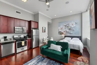 a kitchen with a bed and a green couch in a room at Modern NoLibs Studio - Pool & Gym in Philadelphia