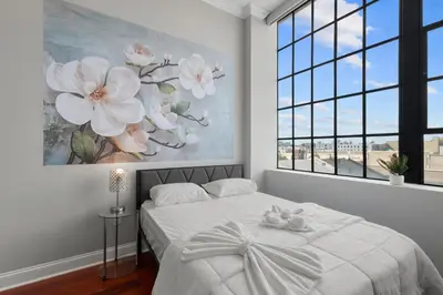a white bedroom with a large flower painting on the wall at Modern NoLibs Studio - Pool & Gym in Philadelphia