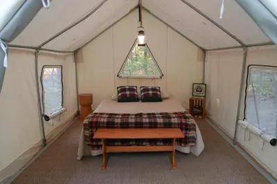 a bedroom in a tent with a bed and a table at Heavens Landing at Moon Valley Campground in Vernon Township