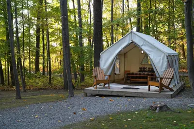 a tent with two chairs and a couch in the woods at Heavens Landing at Moon Valley Campground in Vernon Township