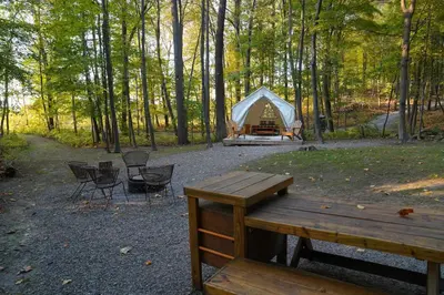 a tent in the woods with chairs and a picnic table at Heavens Landing at Moon Valley Campground in Vernon Township