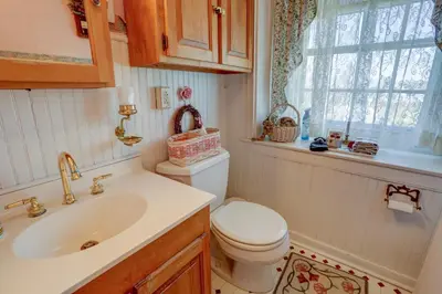 a bathroom with a toilet and a sink and a window at Osceola Mill House Bed and Breakfast in Gordonville